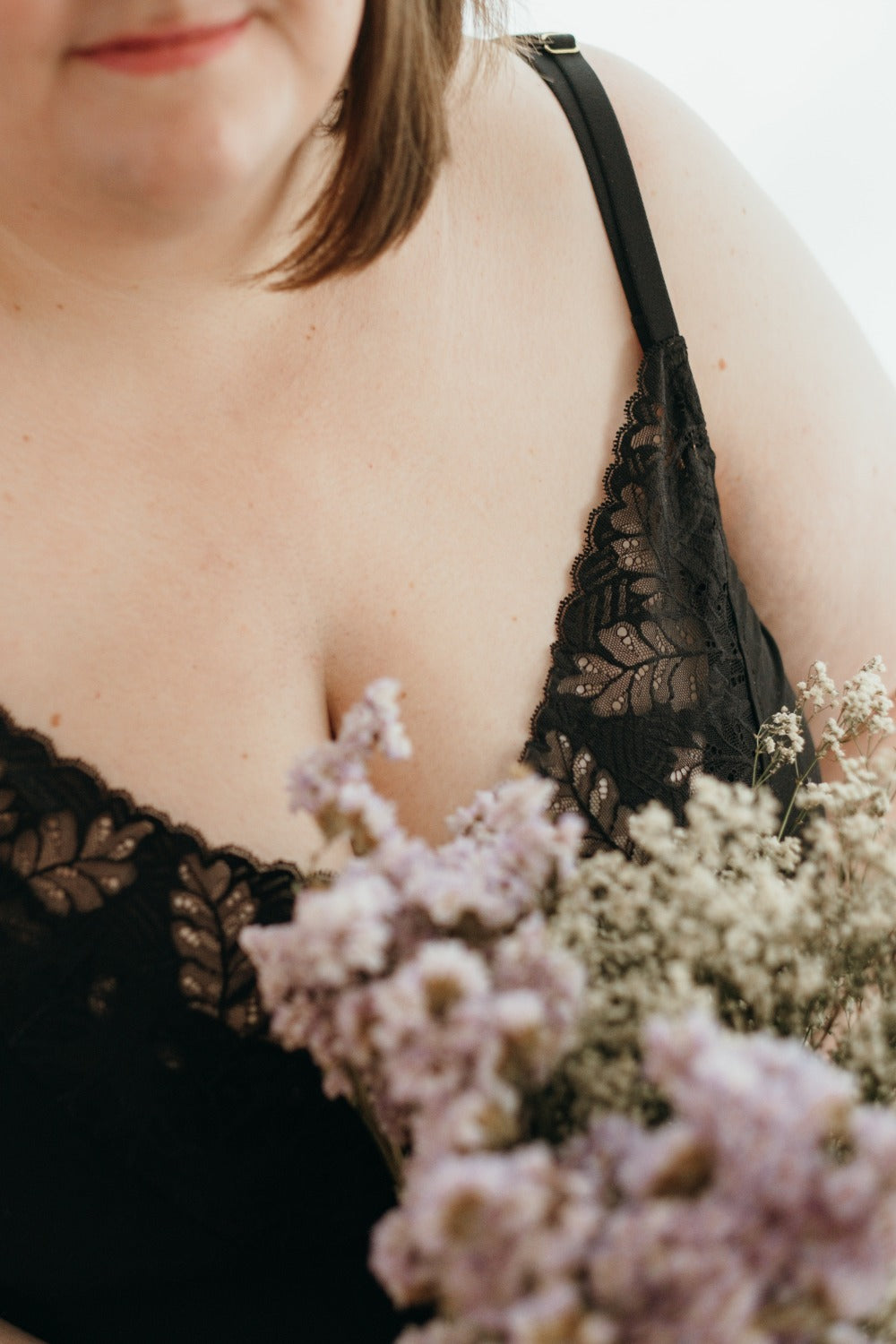 Une femme tient des fleurs à la main et porte des sous-vêtements en dentelle noire